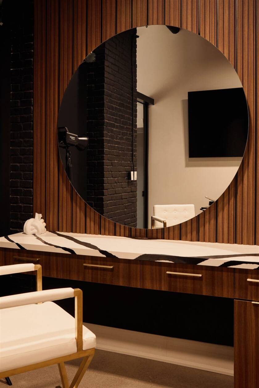 Round mirror vanity station with walnut slat wall